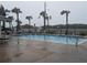 Community pool area with lounge chairs, umbrellas, and swaying palm trees in the background at 3100 Ocean Shore Blvd # 101, Ormond Beach, FL 32176