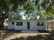 A backyard features a concrete porch and a white home under the shade of leafy trees at 635 Mccormick St, Daytona Beach, FL 32114