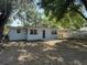 A backyard features a concrete porch and a white home under the shade of leafy trees at 635 Mccormick St, Daytona Beach, FL 32114