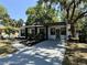 The home's front exterior boasts a walkway, landscaping, and covered parking under shady trees at 635 Mccormick St, Daytona Beach, FL 32114