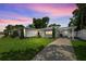 Exterior elevation featuring the front yard, driveway, and landscaping under a colorful twilight sky at 1105 Chichester St, Orlando, FL 32803