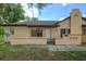 Charming single-story home with tan stucco, a brick fence, dark brown trim, and mature shade trees at 56 Pine Trak # 101E, Ocala, FL 34472