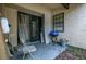 View of the patio with gray chair, blue grill, sliding glass doors, and a small window with security system sign at 56 Pine Trak # 101E, Ocala, FL 34472