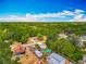 An aerial shot of a lush, tree-filled neighborhood featuring charming homes and a sparkling blue pool at 70 N Oak Ave, Umatilla, FL 32784