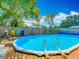 Enjoy the backyard with a large pool, wooden deck, colorful landscaping, and privacy fence at 70 N Oak Ave, Umatilla, FL 32784