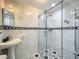 A bathroom view with glass shower, pedestal sink, and black and white decorative border at 70 N Oak Ave, Umatilla, FL 32784