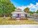 Charming home with unique architecture, a purple door, lovely landscaping, and a decorative fountain at 70 N Oak Ave, Umatilla, FL 32784