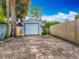 A single-car garage with neutral siding and a simple white garage door stands beside a wooden fence at 70 N Oak Ave, Umatilla, FL 32784