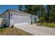 Exterior side view of a home with a two-car garage, and manicured landscaping at 8007 Sw 135Th Loop, Ocala, FL 34473