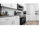 Close-up view of modern kitchen appliances, white cabinets, and granite countertops with backsplash at 8007 Sw 135Th Loop, Ocala, FL 34473