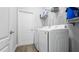 Practical laundry room with white front-load machines, shelving, and a white door at 8007 Sw 135Th Loop, Ocala, FL 34473