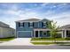Charming two-story blue home with a well-maintained front yard and a driveway leading to an attached garage at 2115 Forage Dr, Kissimmee, FL 34746