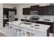 Modern kitchen boasts stainless steel appliances, dark wood cabinets, island with bar seating and stone countertops at 2433 Spring Tune Aly, Kissimmee, FL 34744