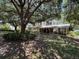 Expansive backyard featuring a screened porch, mature trees, and lush landscaping at 800 W Lake Elbert Ne Dr, Winter Haven, FL 33881
