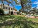 Lovely two-story home with a red door and fountain, enhanced by mature trees and lush lawn at 800 W Lake Elbert Ne Dr, Winter Haven, FL 33881