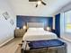 Well-lit primary bedroom with a custom accent wall, ceiling fan, and seating bench at 9971 Highland Sky Aly, Orlando, FL 32832