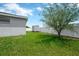 Well-maintained backyard featuring a storage shed, lush lawn, white fence, and a mature tree for shade and privacy at 305 St Georges Cir, Eagle Lake, FL 33839