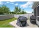 Backyard featuring a concrete patio, grill, green lawn, and white privacy fence, offering a secluded outdoor space at 305 St Georges Cir, Eagle Lake, FL 33839