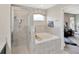 A tiled bathroom offers a built-in tub and separate shower stall with a seat at 305 St Georges Cir, Eagle Lake, FL 33839