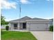 Charming single Gathering home with a well-manicured lawn, gray paint, and a two-car garage at 305 St Georges Cir, Eagle Lake, FL 33839