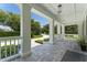 Inviting covered front porch with stone tile flooring and white columns at 5500 W Lake Butler Rd, Windermere, FL 34786