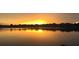 Golden sunset reflecting on the lake offering a serene view with silhouettes of nearby houses at 5500 W Lake Butler Rd, Windermere, FL 34786