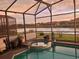 Backyard pool and spa with enclosure offer relaxation and view of lake at sunset at 1030 Marcello Blvd, Kissimmee, FL 34746