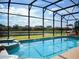 Gorgeous screened pool and jacuzzi with a backdrop of a scenic pond and blue sky at 1030 Marcello Blvd, Kissimmee, FL 34746