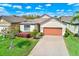 Attractive one-story home with a well-maintained lawn, landscaping and an orange two-car garage door at 518 Cortez Dr, Davenport, FL 33837