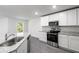 Modern kitchen boasts stainless appliances, granite counters, and sleek gray wood-look flooring at 567 Bay Leaf Dr, Poinciana, FL 34759