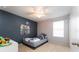Comfortable bedroom with a modern accent wall, ceiling fan, and natural light from a window at 14563 Bahama Swallow Blvd, Winter Garden, FL 34787