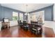 A dining room featuring hardwood floors, blue accent wall, and wainscotting leading to the main entrance and staircase at 14563 Bahama Swallow Blvd, Winter Garden, FL 34787