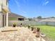 Backyard brick patio featuring plants in pots on pedestals, a vinyl fence, and a green lawn at 159 Lazy Willow Dr, Davenport, FL 33897