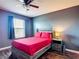 Bedroom featuring a ceiling fan, window with blinds, and a wooden frame bed with red linens at 159 Lazy Willow Dr, Davenport, FL 33897