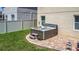 Backyard area with brick patio featuring hot tub, green grass, and a fence line at 159 Lazy Willow Dr, Davenport, FL 33897