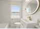 Stylish bathroom featuring a vanity, updated fixtures, a round mirror, and tiled walls around the bathtub at 2013 Pineway Dr, Orlando, FL 32839