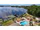 Aerial shot of a pool and gazebo overlooking a lake with a dock and green space at 640 Lake Dexter Cir, Winter Haven, FL 33884