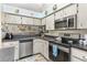 A kitchen featuring white cabinets, stainless steel appliances, and a sink overlooking the living area at 640 Lake Dexter Cir, Winter Haven, FL 33884