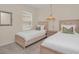 Bedroom showcasing twin beds, neutral decor, and a unique light fixture at 7634 Oakmoss Loop, Davenport, FL 33837
