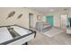 Bright game room with a comfortable gray couch, an air hockey table, and neutral-toned walls and flooring at 7634 Oakmoss Loop, Davenport, FL 33837