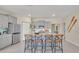 The open kitchen features a large island with bar seating, gray cabinets, stainless appliances, and a tiled island accent at 7634 Oakmoss Loop, Davenport, FL 33837