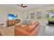 Charming living room with a comfortable leather couch, TV, and natural lighting at 7634 Oakmoss Loop, Davenport, FL 33837