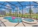 Lovely screened-in pool area with a jacuzzi, beautiful landscaping, and an inviting flamingo float at 7634 Oakmoss Loop, Davenport, FL 33837
