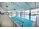 Indoor swimming pool with clear blue water, bright natural light, and large windows overlooking green landscape at 8691 Sw 57Th Ln, Ocala, FL 34481