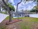 Peaceful backyard with a screened pool enclosure, white fence, and trees providing shade at 1634 Lady Bowers Trl, Lakeland, FL 33809