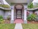 Inviting front porch featuring elegant columns, double doors with wreaths, and manicured landscaping, creating a warm entry at 1634 Lady Bowers Trl, Lakeland, FL 33809