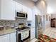 Gourmet kitchen featuring stainless steel appliances, granite countertops, and stylish backsplash at 1634 Lady Bowers Trl, Lakeland, FL 33809