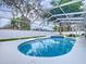 A covered pool with blue tile accenting the edge. Trees can be seen through the screen at 1634 Lady Bowers Trl, Lakeland, FL 33809