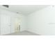 A minimalist bedroom with plush gray carpeting, featuring a bright bathroom visible through an open doorway at 2071 Babbling Brook Blvd, Auburndale, FL 33823