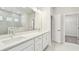 Modern bathroom with double sinks, white cabinets, and tiled walk-in shower at 16994 Cedar Valley Cir, Clermont, FL 34711